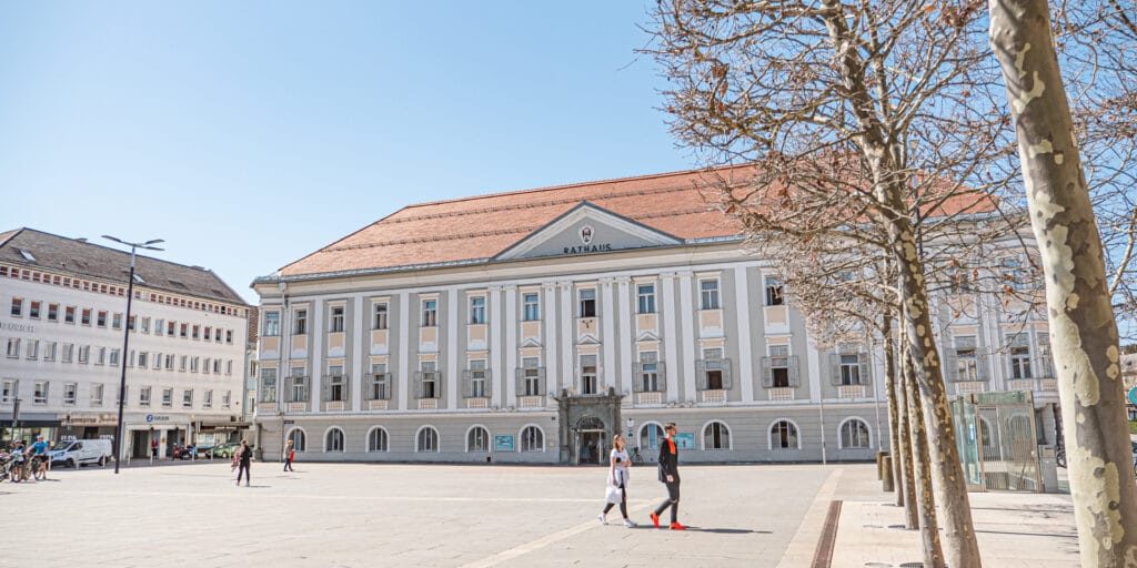 Vorplatz des Rathaus Klagenfur an einem sonnigen Tag mit wenigen Menschen